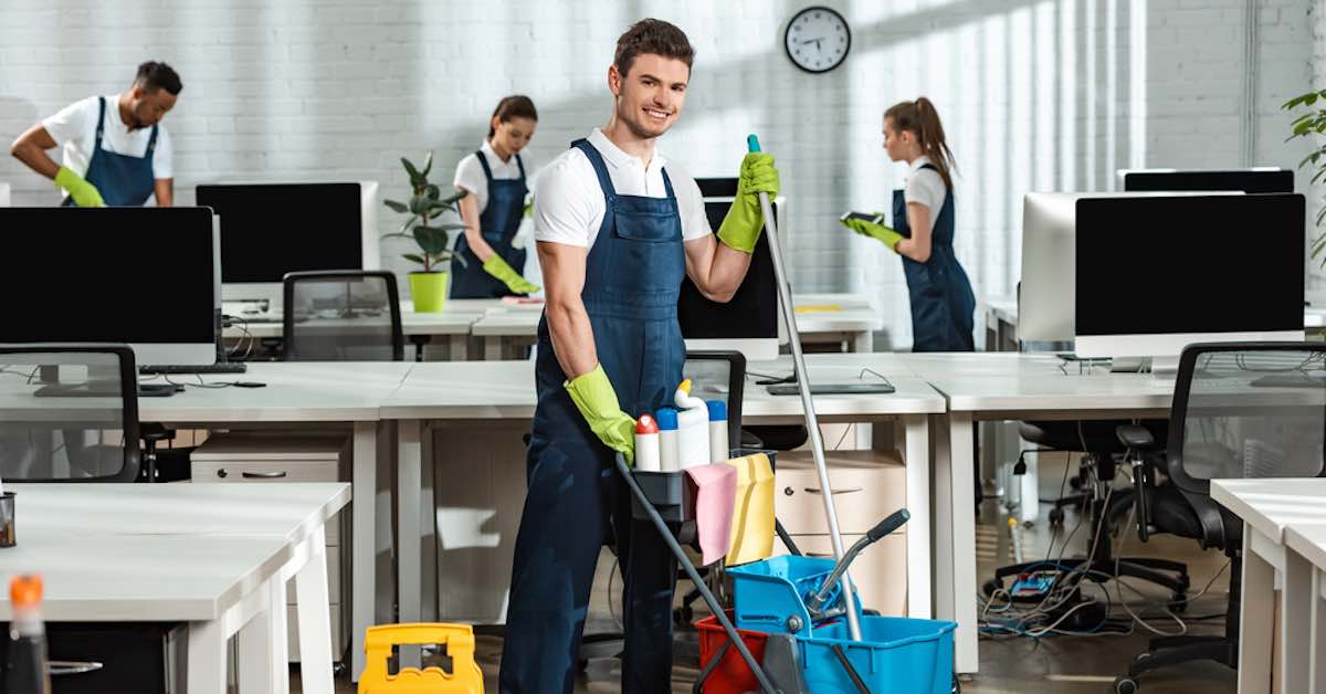 A Cleaner with a broom smiling